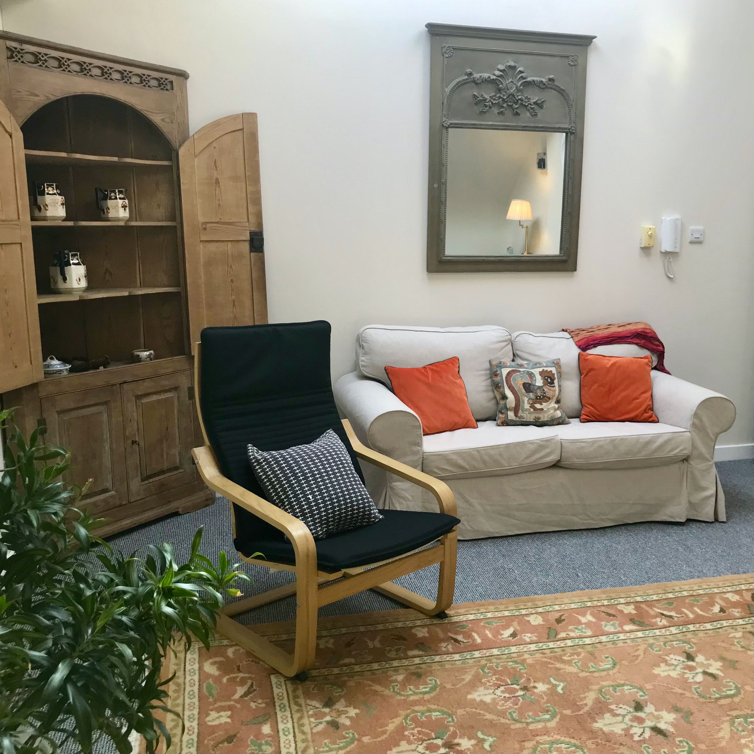 Therapy room with chair, sofa and a corner cupboard at The Practice Rooms in Stokes Croft, Bristol