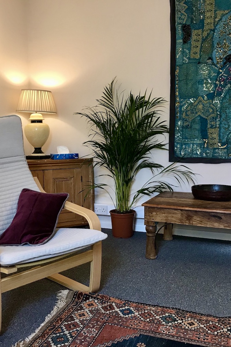 Chair, plant and wooden tables in a therapy room at The Practice Rooms in Clifton, Bristol