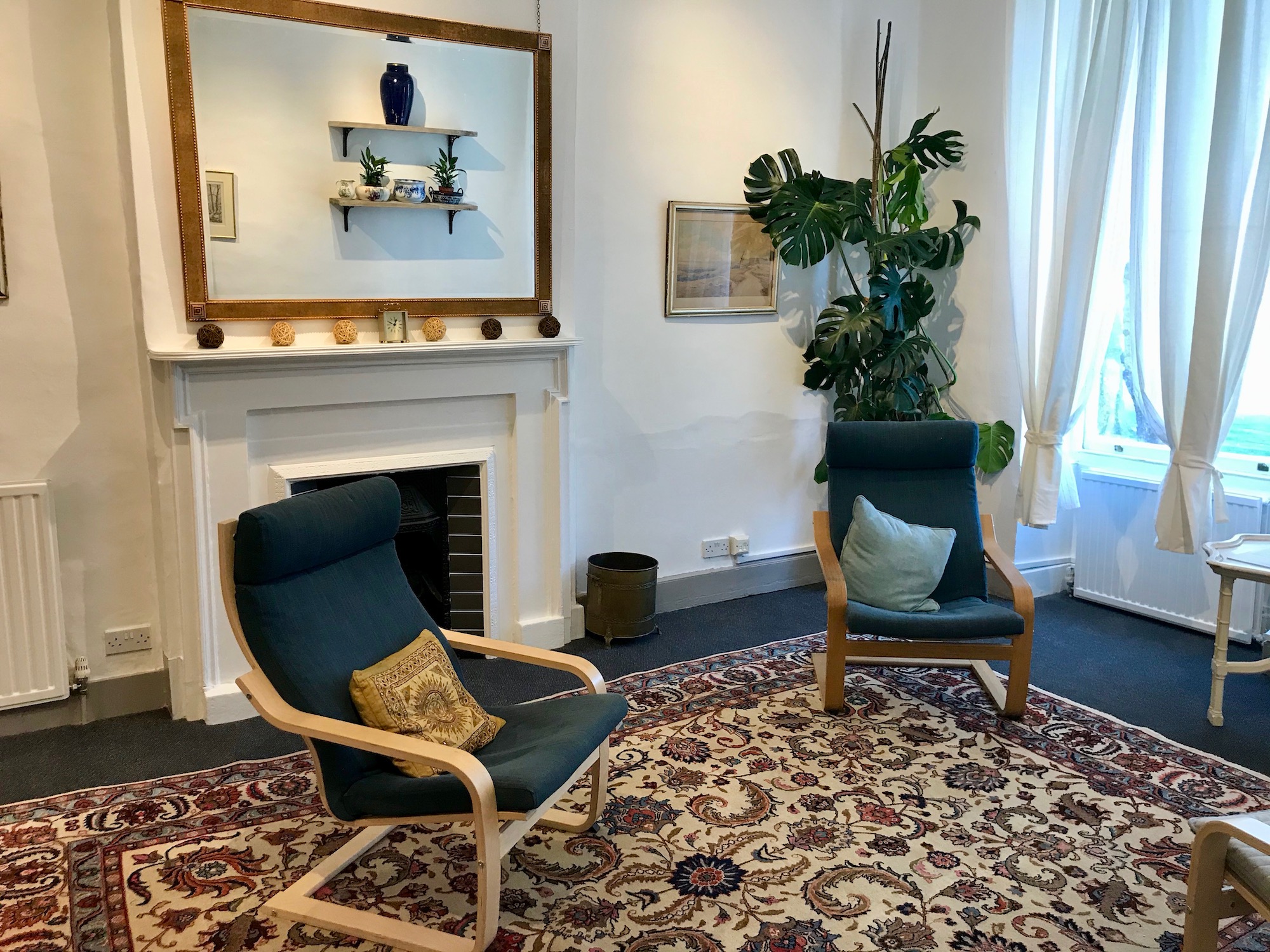 Therapy room with chairs, fireplace and a large mirror at The Practice Rooms in Queen Square, Bristol