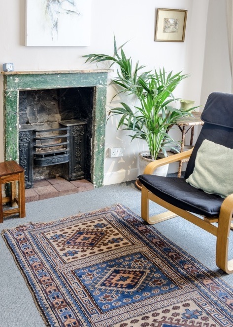 Therapy room with chair, plant and green fireplace at The Practice Rooms in Westbury-on-Trym, Bristol