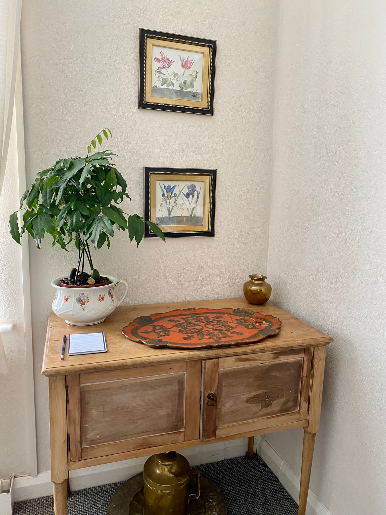 Wooden table with a plant, orange tray and pictures on the wall