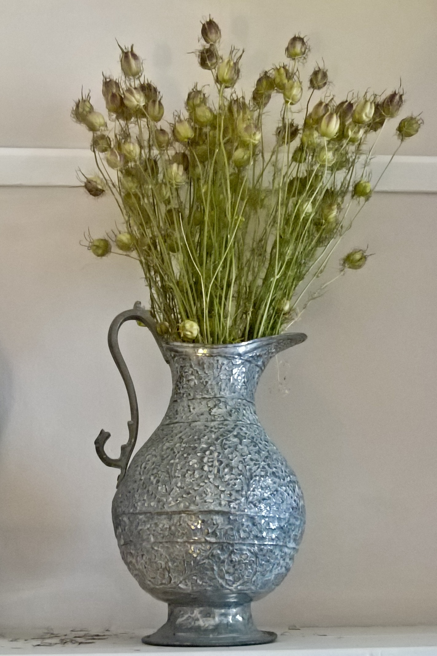 A metal jug with dried flowers